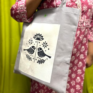 A picture of a person carrying a grey tote bag with a black and white bird design on it